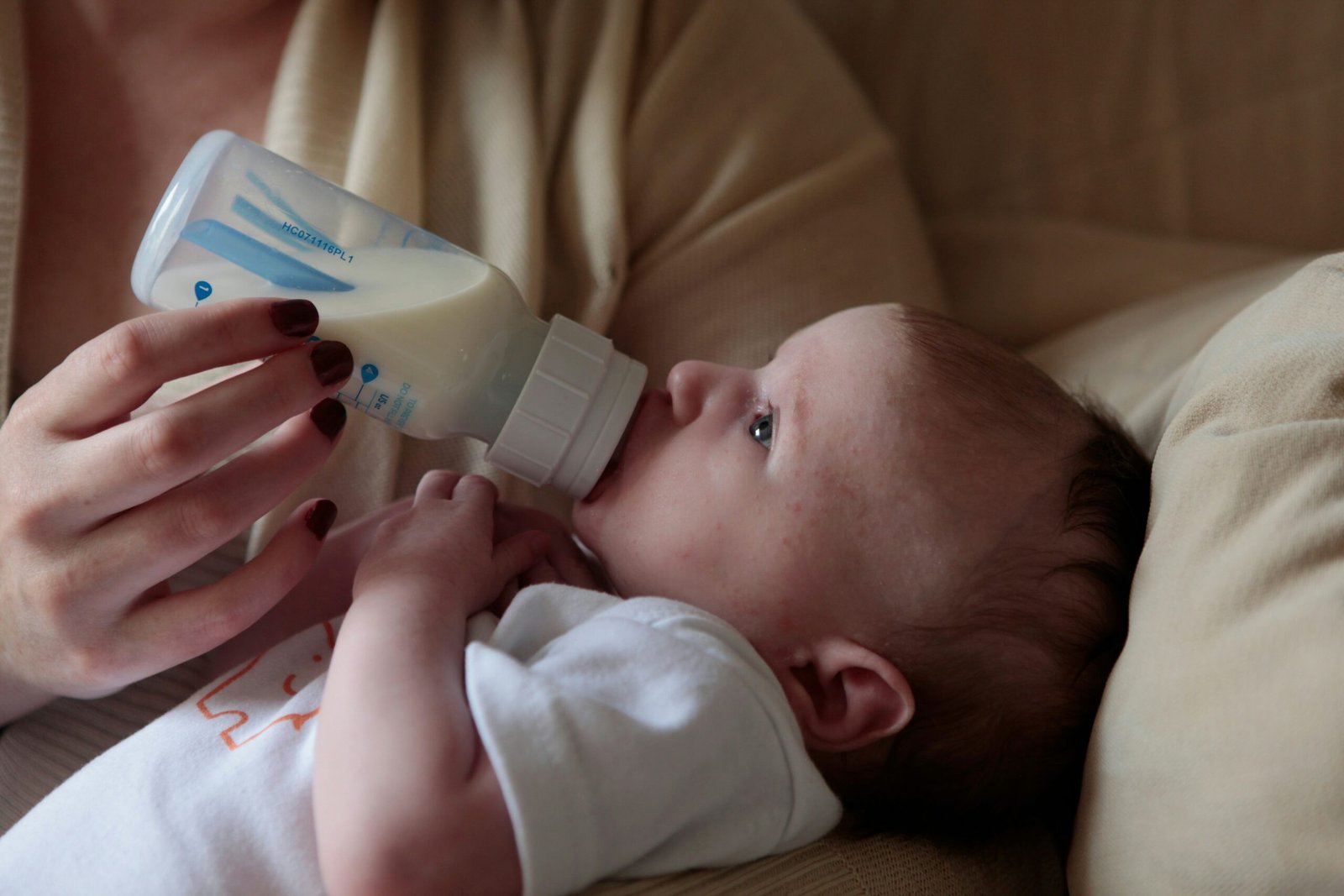 A baby's face beside a caregiver's steadying hand